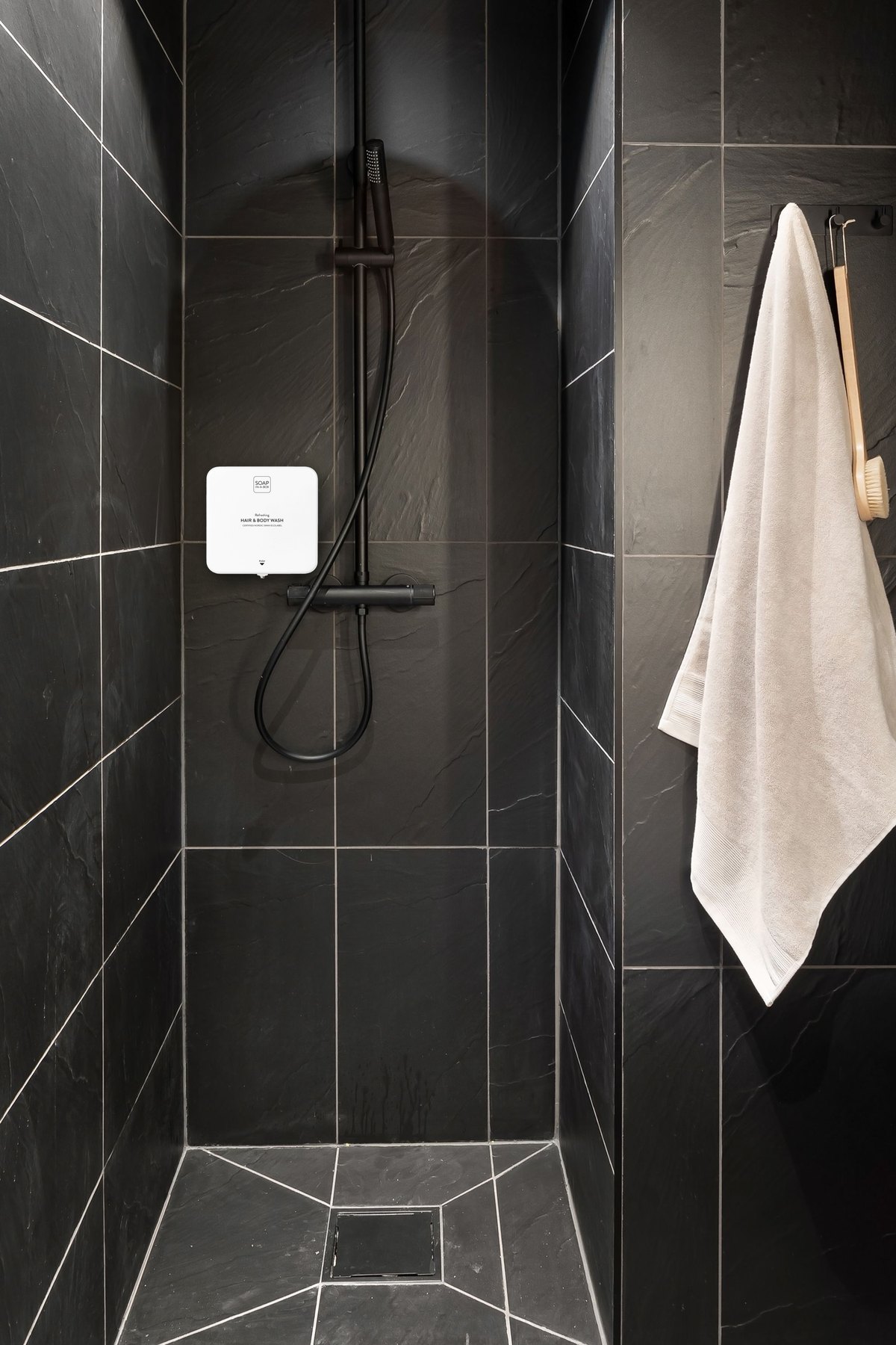 Vit Soap In A Box-dispenser på svart skifferkakel i hotelldusch